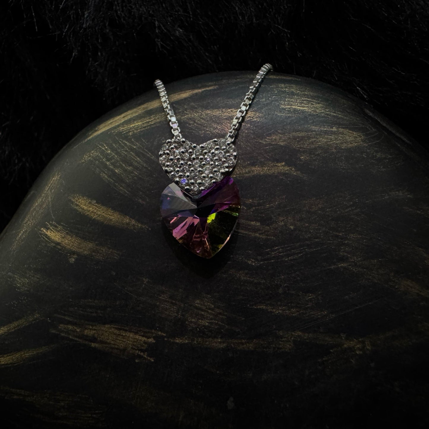 A stunning sterling silver necklace featuring a multicolored heart-shaped crystal pendant paired with a smaller, cubic zirconia-encrusted heart charm, elegantly displayed against a dark background.