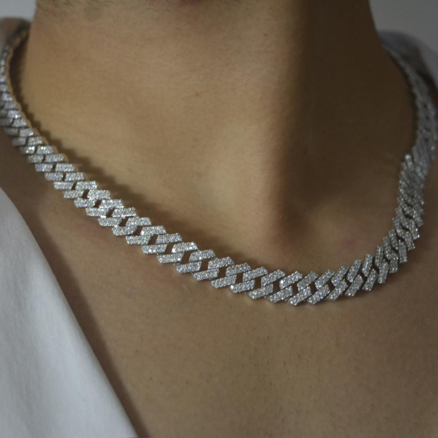 Close-up of a shimmering 925 silver iced-out Cuban chain necklace worn on the neck, styled with a white shirt.
