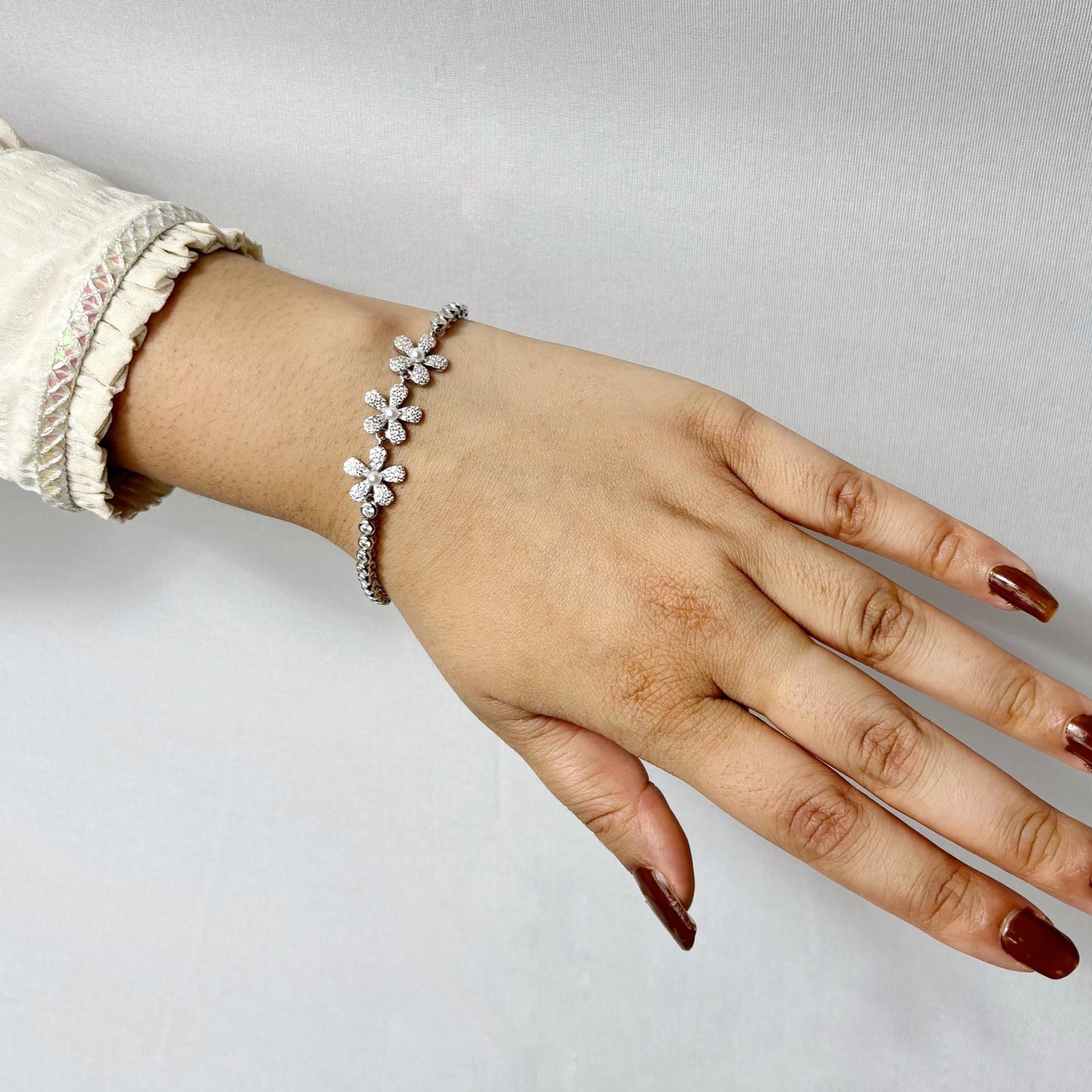 925 sterling silver bracelet with delicate daisy flower motifs made of CZ stones, elegantly styled on a woman's wrist.