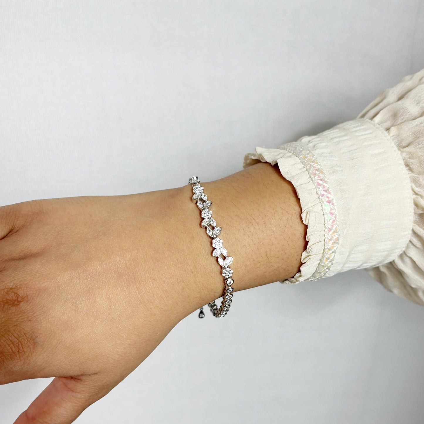 Delicate 925 sterling silver bracelet with marquise and round-cut CZ stones arranged in a floral pattern, worn on a woman's wrist.