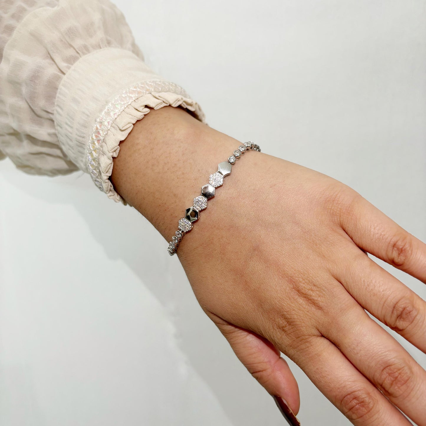 A stylish 925 sterling silver bracelet featuring alternating hexagon-shaped beads with polished and textured finishes, worn on a woman’s wrist.