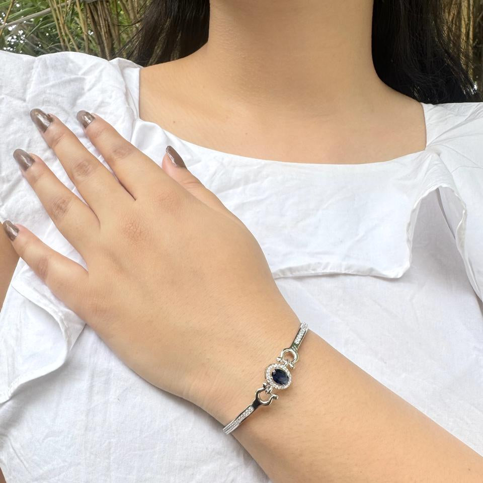 A 925 sterling silver bracelet featuring an oval sapphire-blue stone surrounded by small diamonds