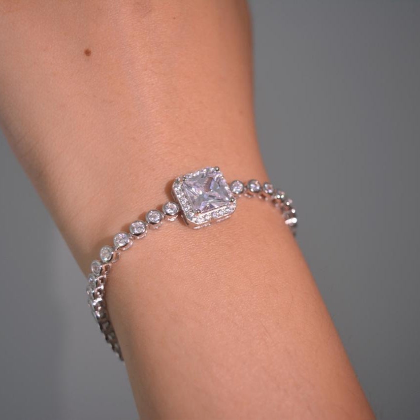 Close-up of a 925 sterling silver bracelet with a large square-cut solitaire center stone and bezel-set round zircon accents.