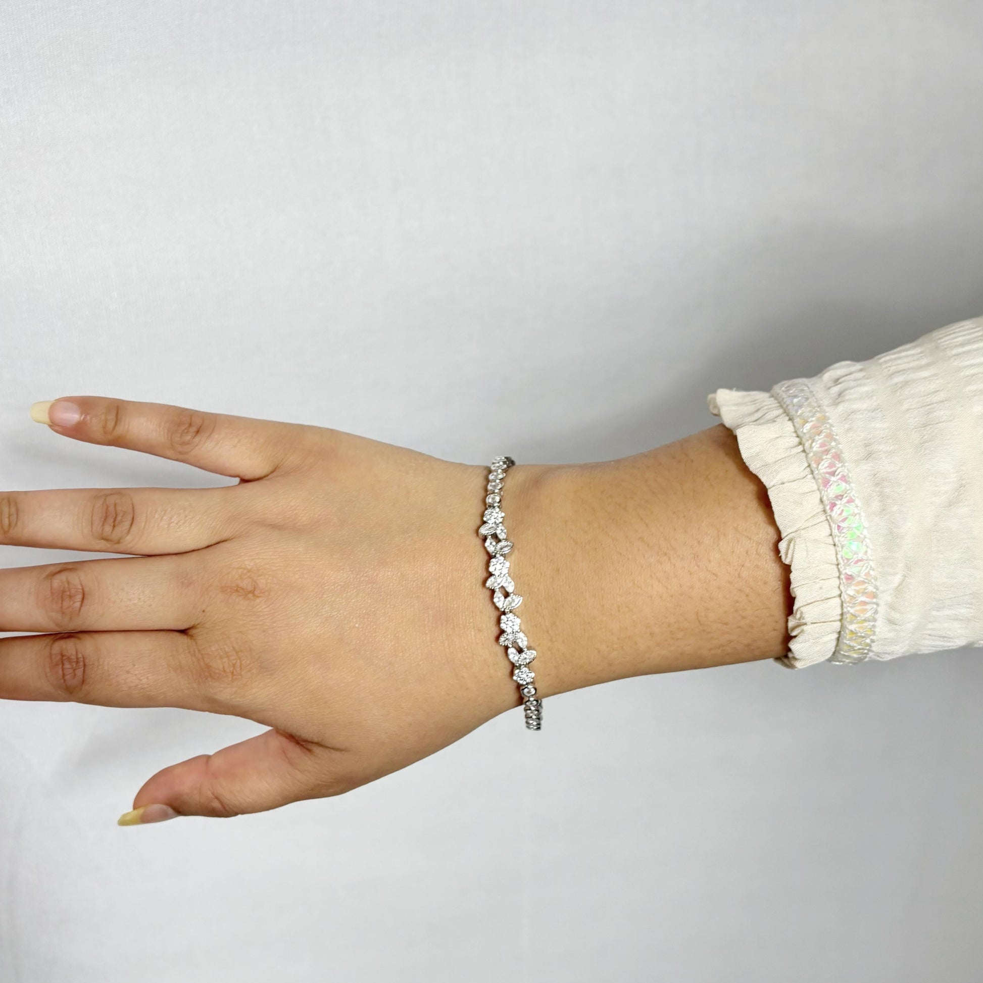 Delicate 925 sterling silver bracelet with marquise and round-cut CZ stones arranged in a floral pattern, worn on a woman's wrist.