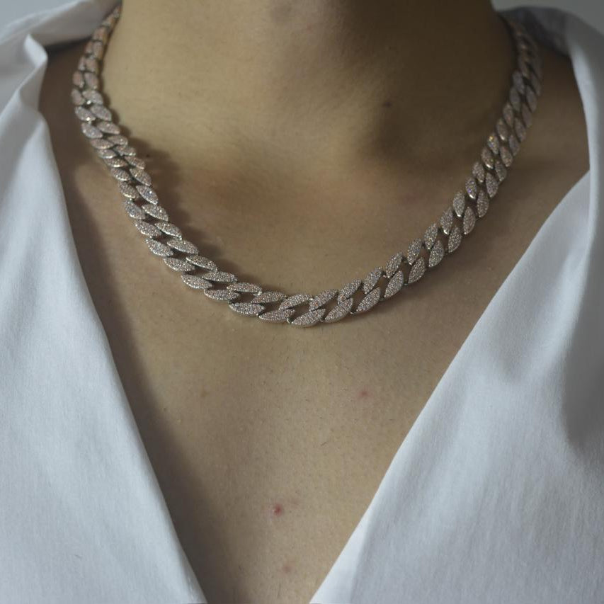 Rose gold tone Cuban link necklace encrusted with sparkling zircon stones on a model wearing a white V-neck top.