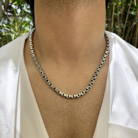 A sleek box link sterling silver necklace worn on the neck, emphasizing its modern and refined design.