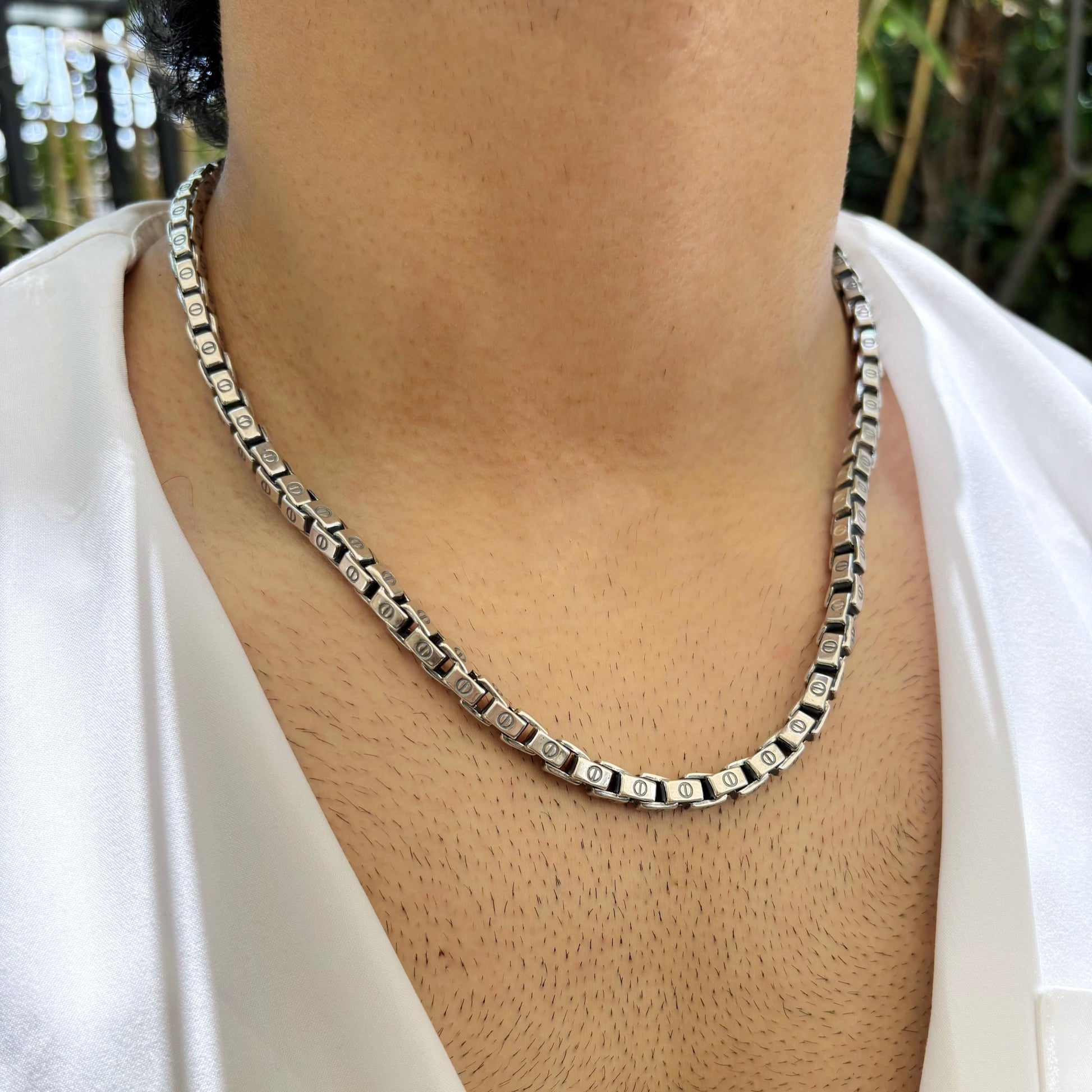 A sleek box link sterling silver necklace worn on the neck, emphasizing its modern and refined design.
