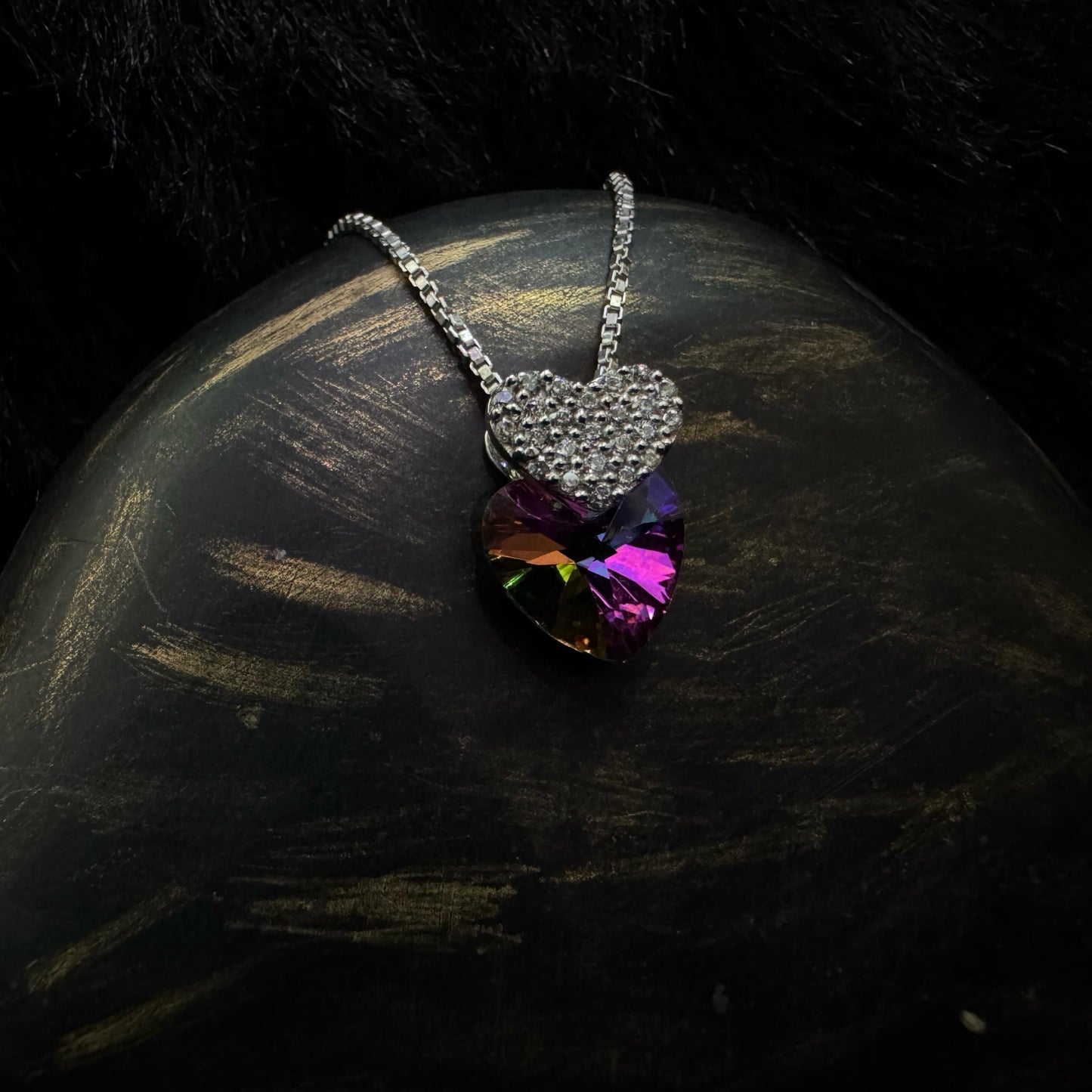 A stunning sterling silver necklace featuring a multicolored heart-shaped crystal pendant paired with a smaller, cubic zirconia-encrusted heart charm, elegantly displayed against a dark background.