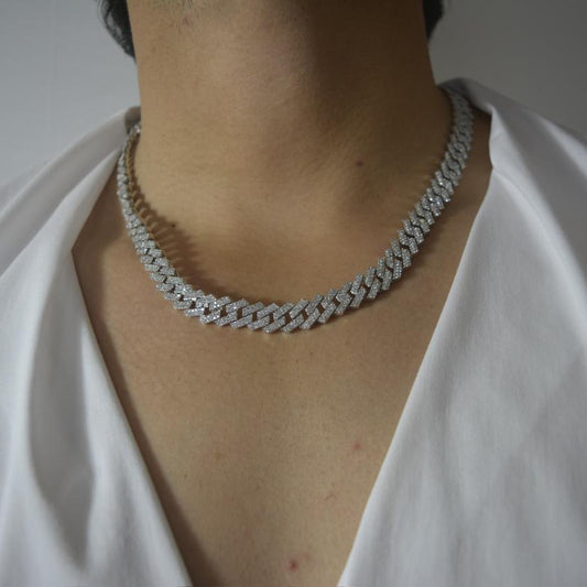 Close-up of a shimmering 925 silver iced-out Cuban chain necklace worn on the neck, styled with a white shirt.
