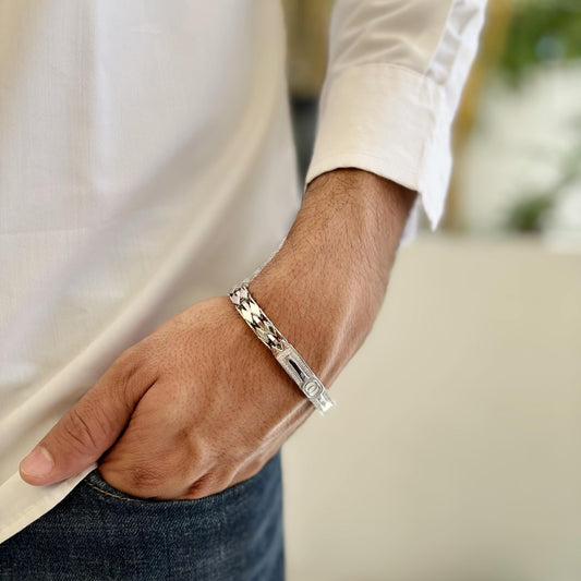 A stylish sterling silver bracelet with a chevron pattern and a sleek centerpiece, worn on a man’s wrist showcasing elegance and sophistication.
