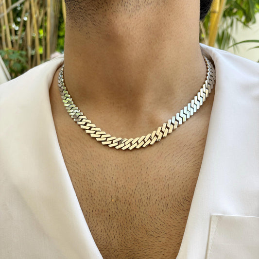A sleek and polished Cuban link sterling silver chain worn around the neck, showcasing its elegant and timeless design.