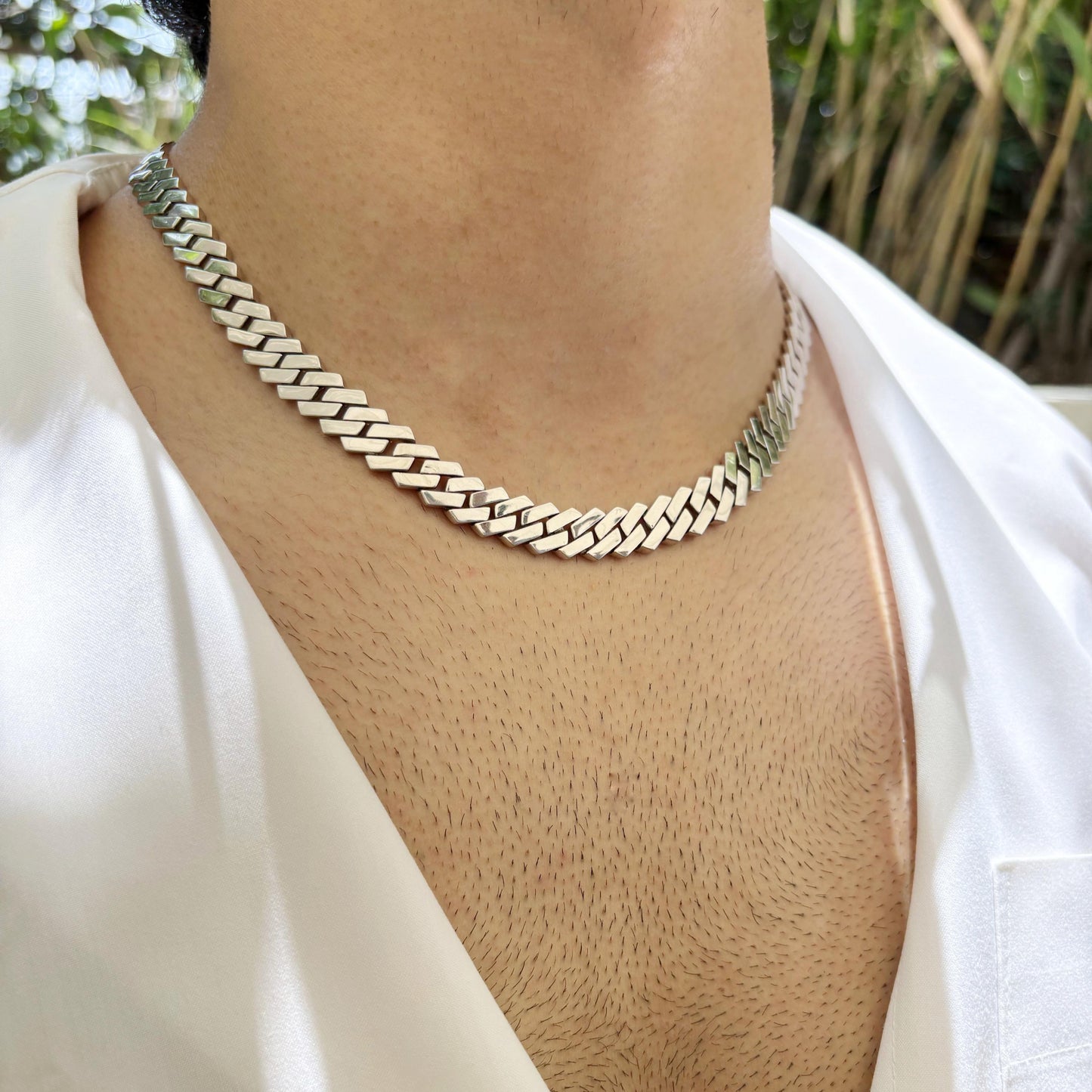 A sleek and polished Cuban link sterling silver chain worn around the neck, showcasing its elegant and timeless design.