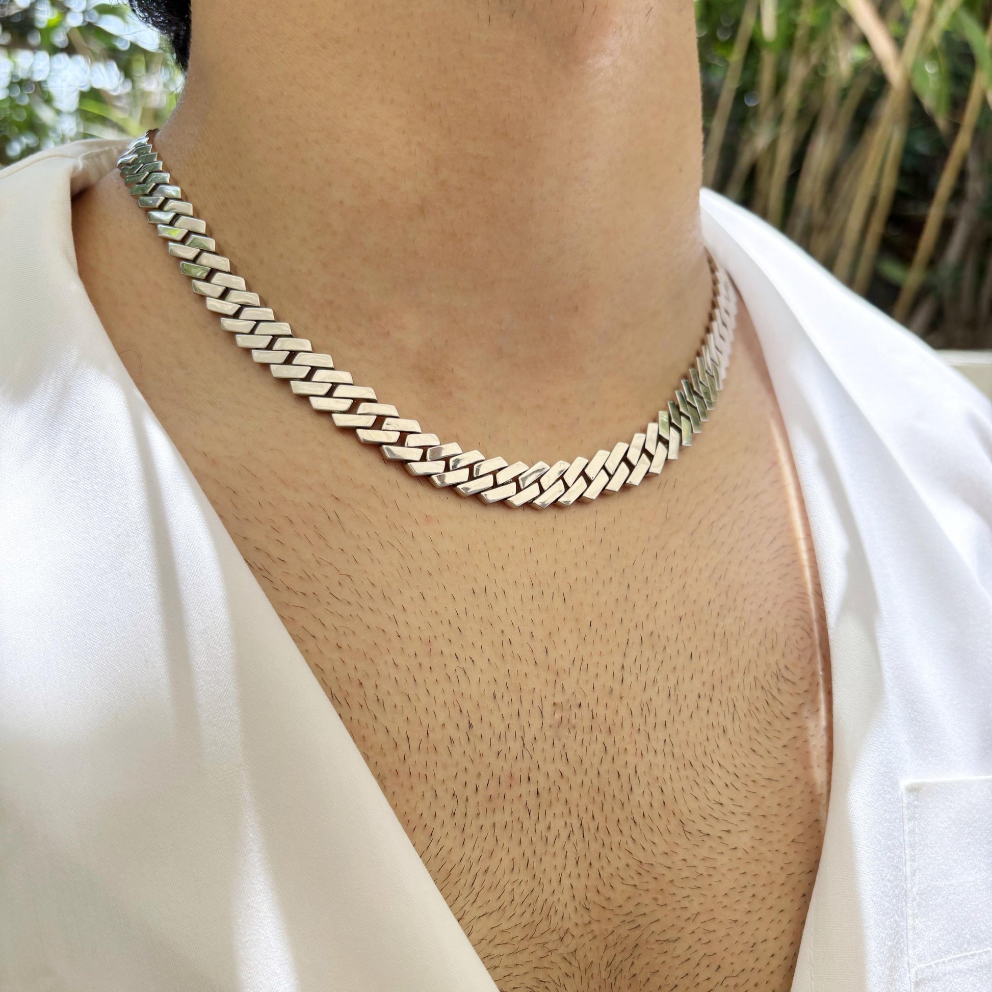A sleek and polished Cuban link sterling silver chain worn around the neck, showcasing its elegant and timeless design.