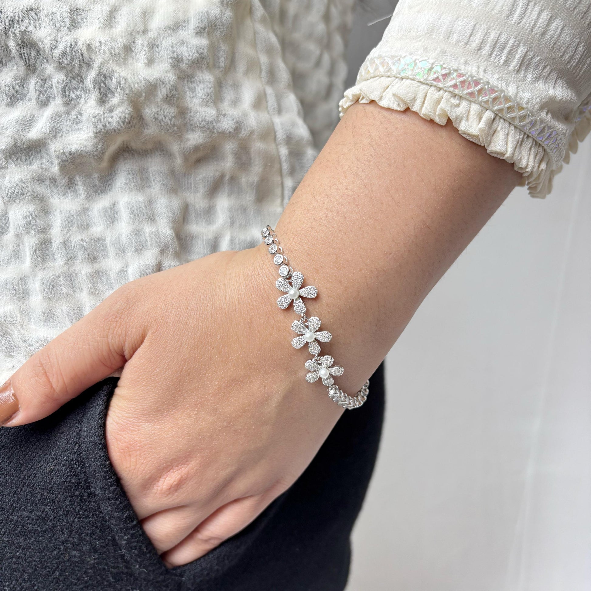 925 sterling silver bracelet with delicate daisy flower motifs made of CZ stones, elegantly styled on a woman's wrist.