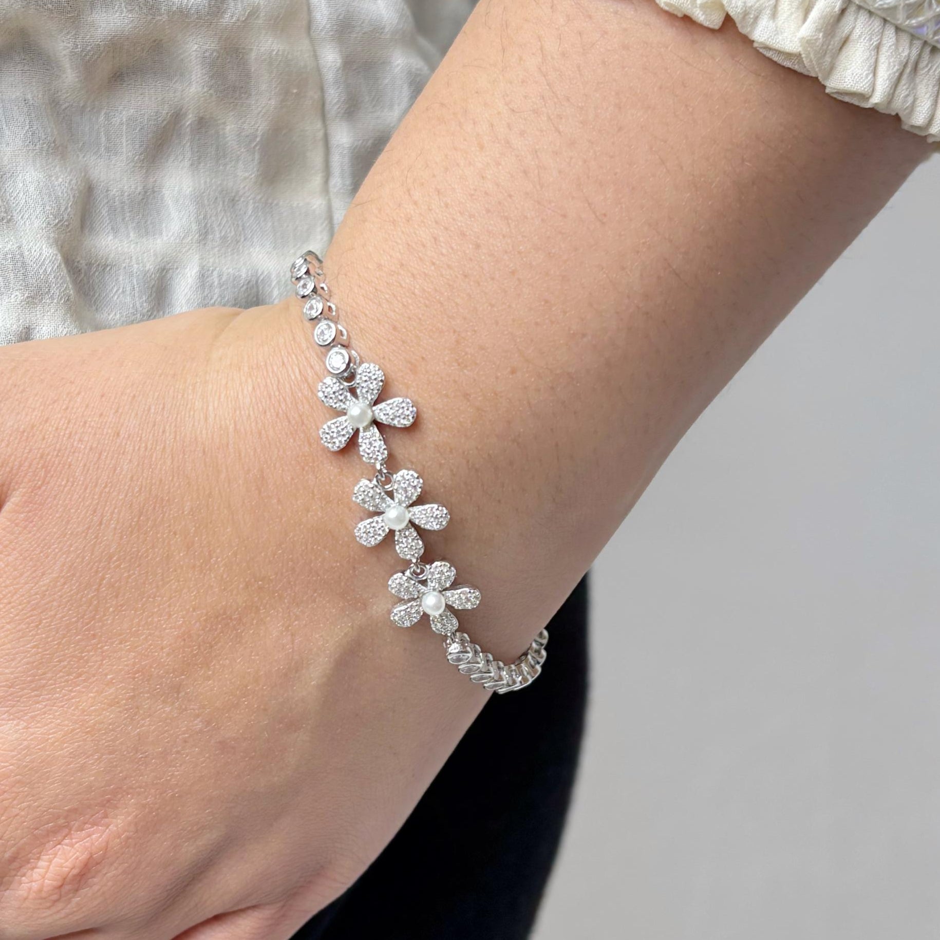 925 sterling silver bracelet with delicate daisy flower motifs made of CZ stones, elegantly styled on a woman's wrist.