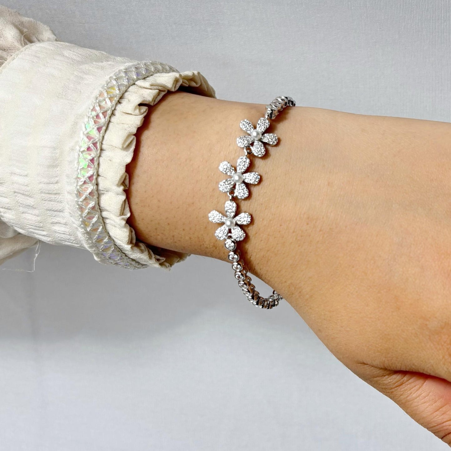 925 sterling silver bracelet with delicate daisy flower motifs made of CZ stones, elegantly styled on a woman's wrist.