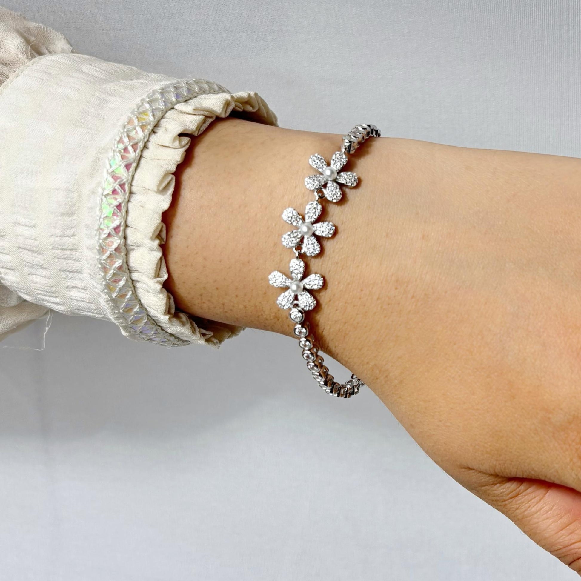 925 sterling silver bracelet with delicate daisy flower motifs made of CZ stones, elegantly styled on a woman's wrist.