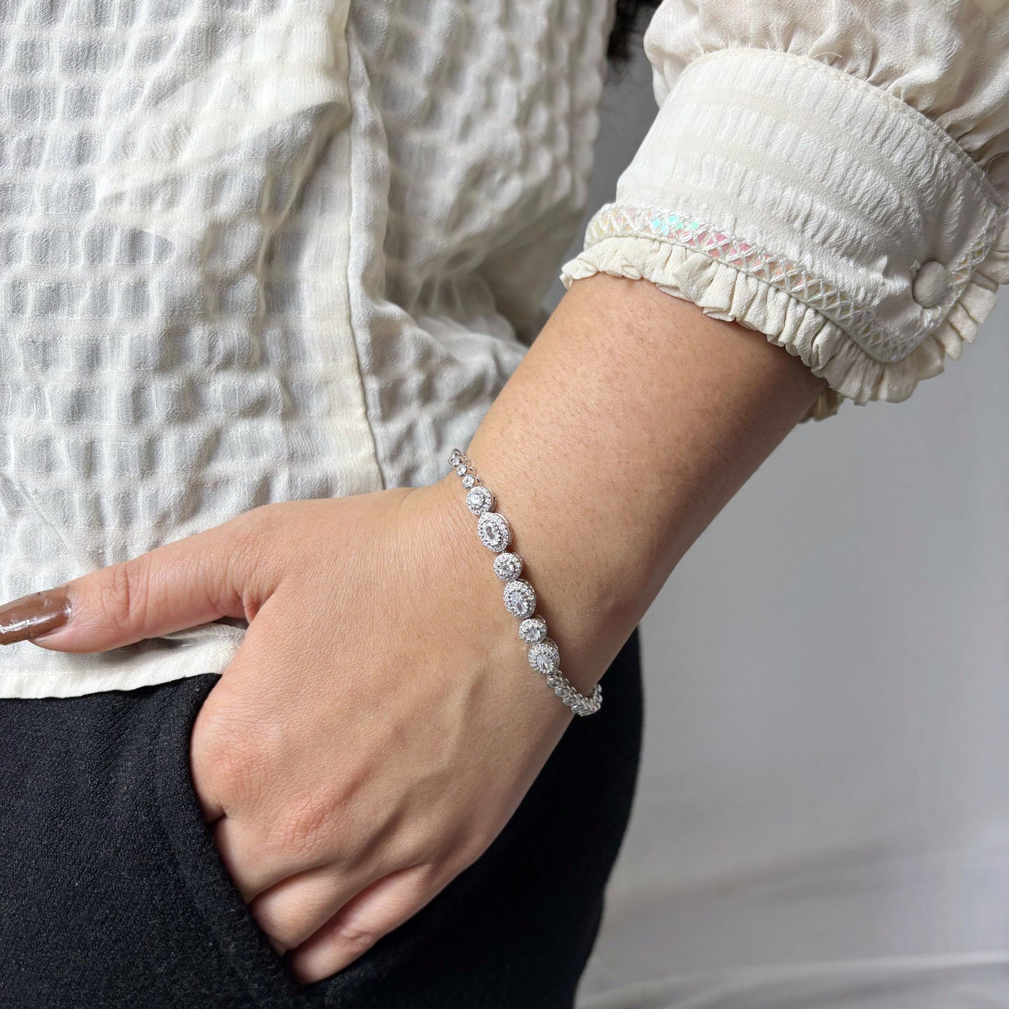 Elegant 925 sterling silver bracelet with circular halo-set CZ stones, worn on a woman's wrist against a soft neutral background.