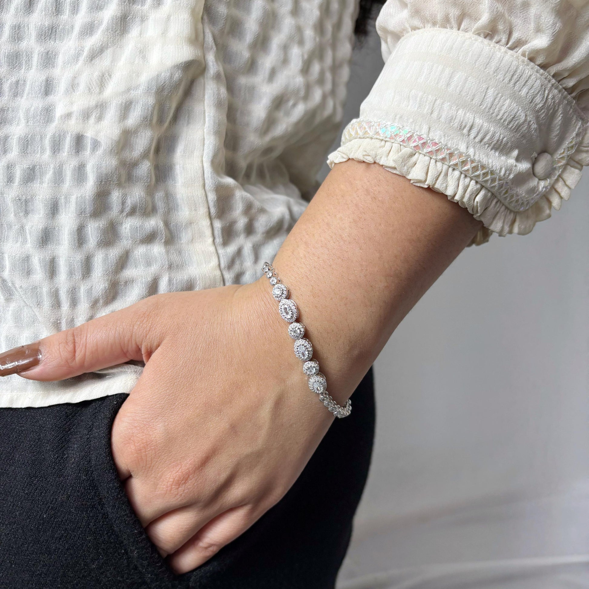 Elegant 925 sterling silver bracelet with circular halo-set CZ stones, worn on a woman's wrist against a soft neutral background.