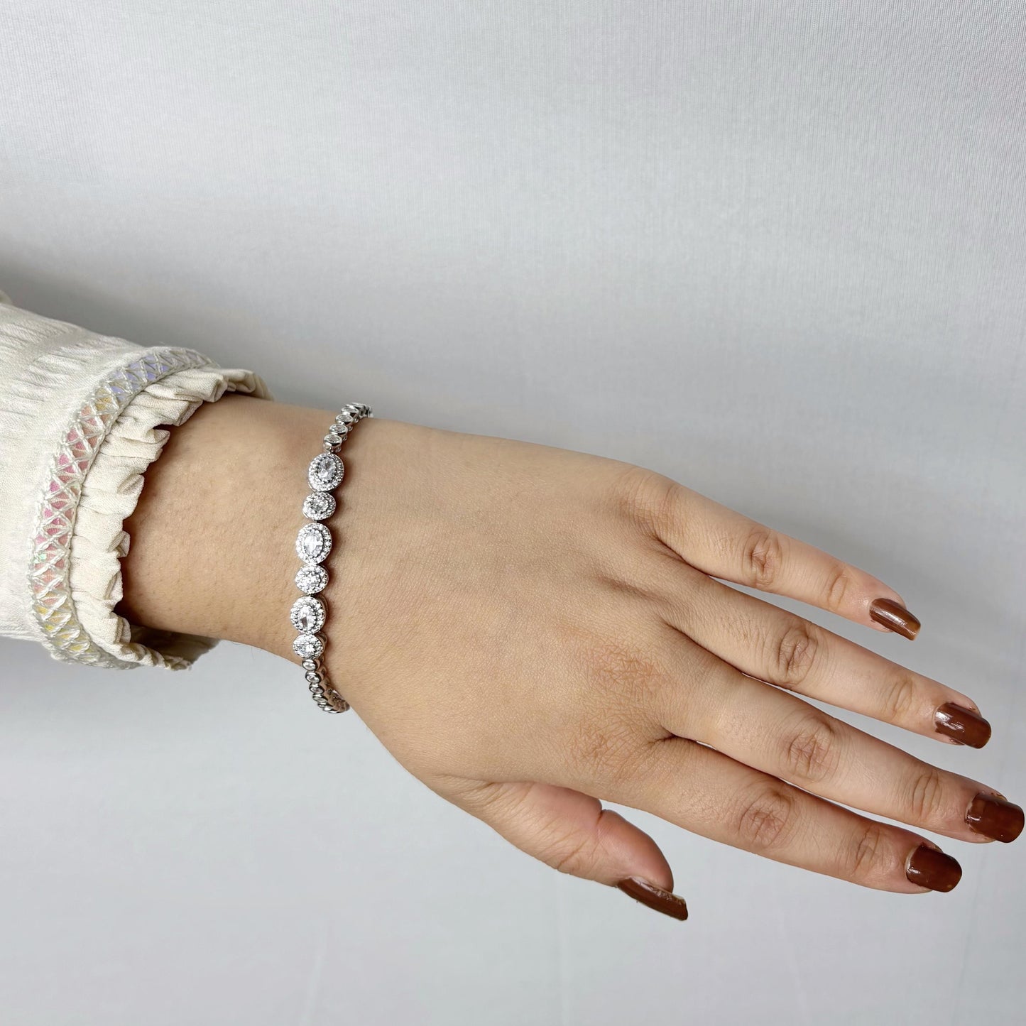 Elegant 925 sterling silver bracelet with circular halo-set CZ stones, worn on a woman's wrist against a soft neutral background.