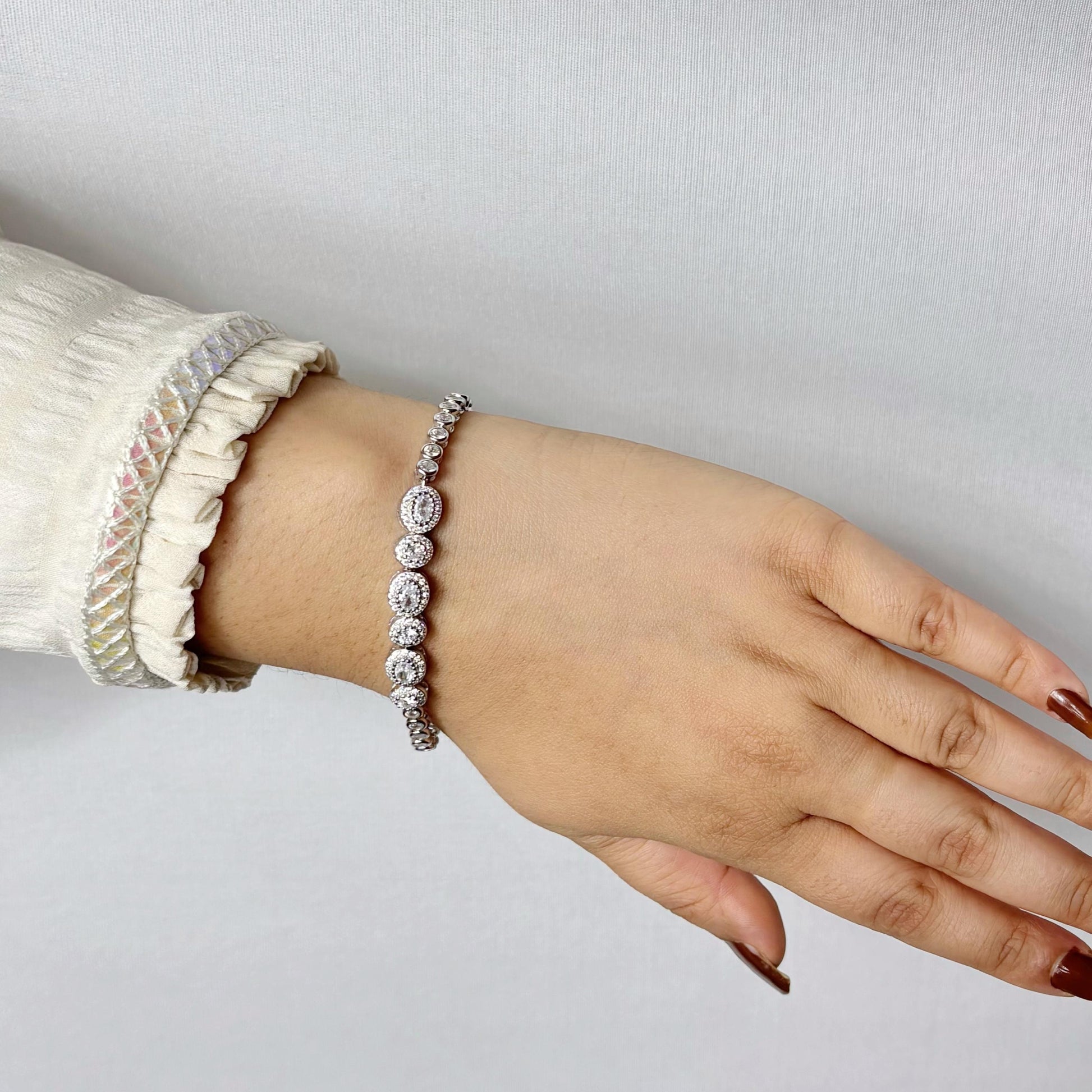 Elegant 925 sterling silver bracelet with circular halo-set CZ stones, worn on a woman's wrist against a soft neutral background.