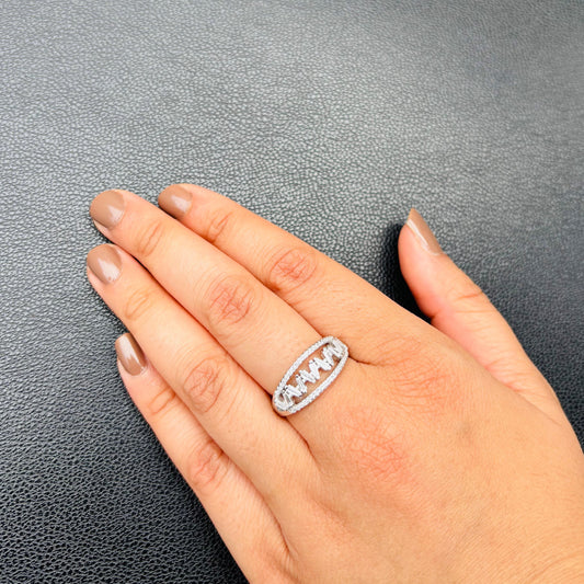 An exquisite sterling silver ring with an oval cutwork design encrusted with sparkling CZ stones, styled on a hand against a textured black background.