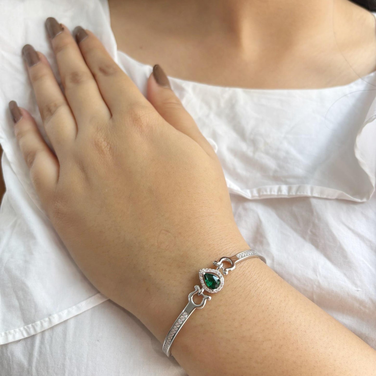 A 925 sterling silver bracelet featuring a teardrop-shaped emerald-green stone surrounded by a halo of zircon accents.