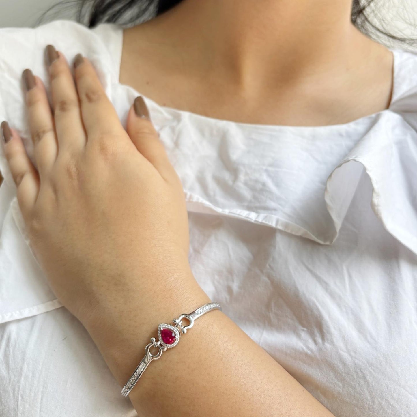 A 925 sterling silver bracelet featuring a teardrop-shaped emerald-pink stone surrounded by a halo of zircon accents.