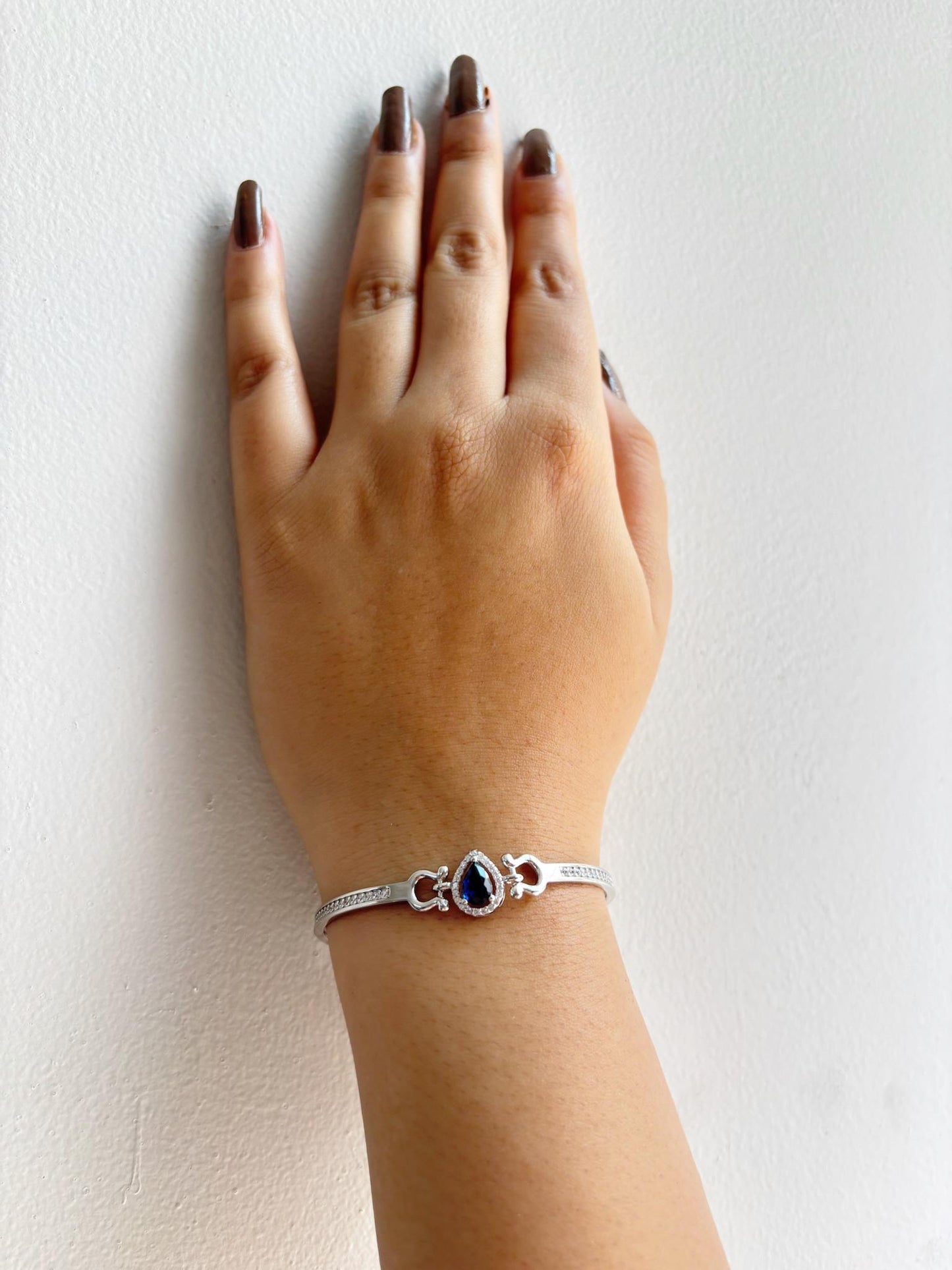 A 925 sterling silver bracelet featuring a teardrop-shaped emerald-blue stone surrounded by a halo of zircon accents.