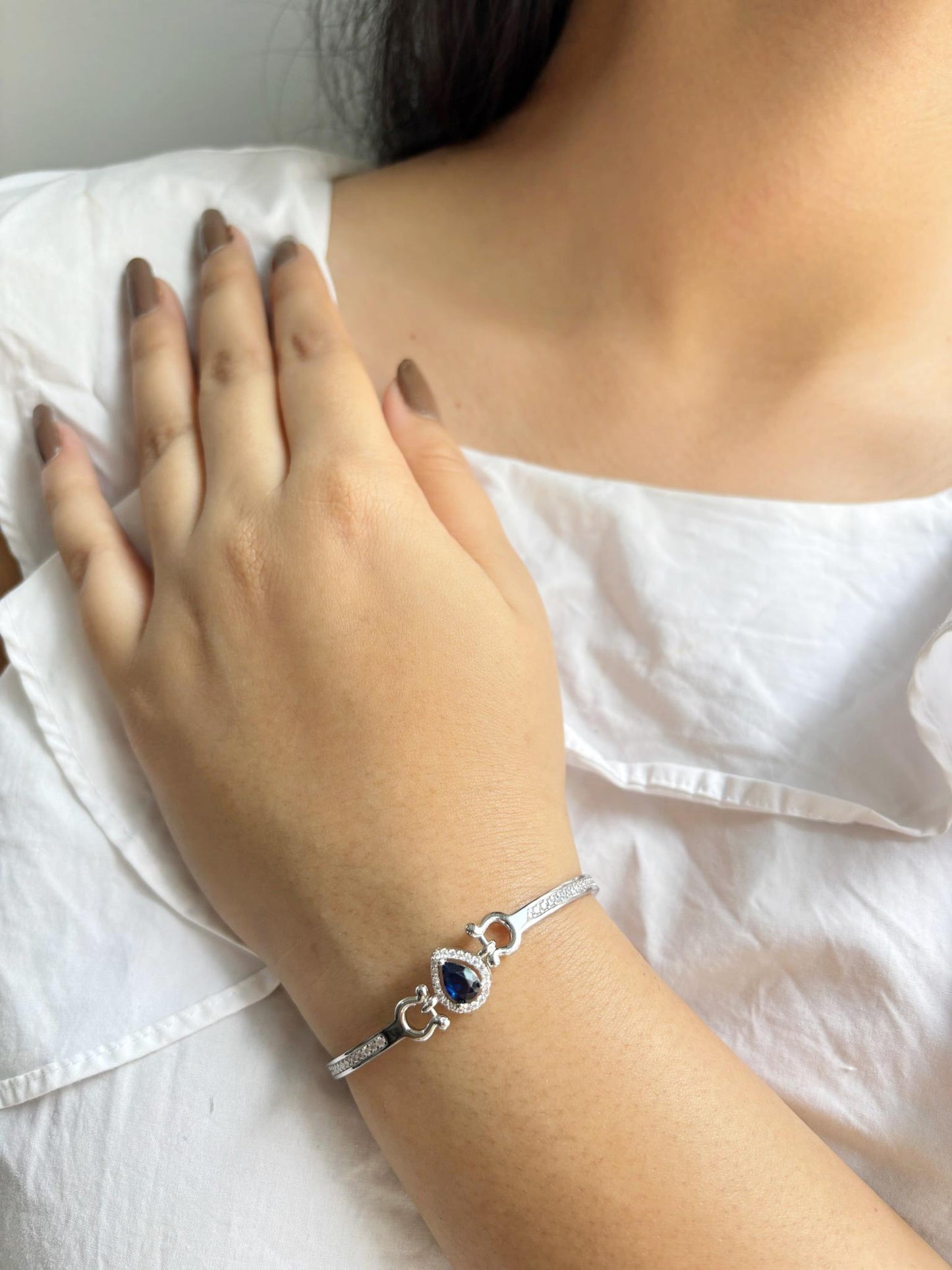 A 925 sterling silver bracelet featuring a teardrop-shaped emerald-blue stone surrounded by a halo of zircon accents.