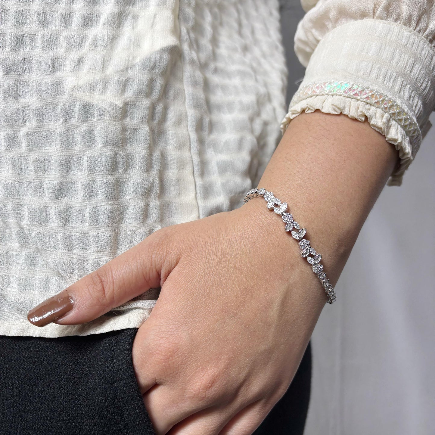 Delicate 925 sterling silver bracelet with marquise and round-cut CZ stones arranged in a floral pattern, worn on a woman's wrist.