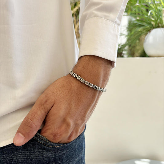 A sleek sterling silver bracelet with a maze-inspired design, showcased on a man's wrist paired