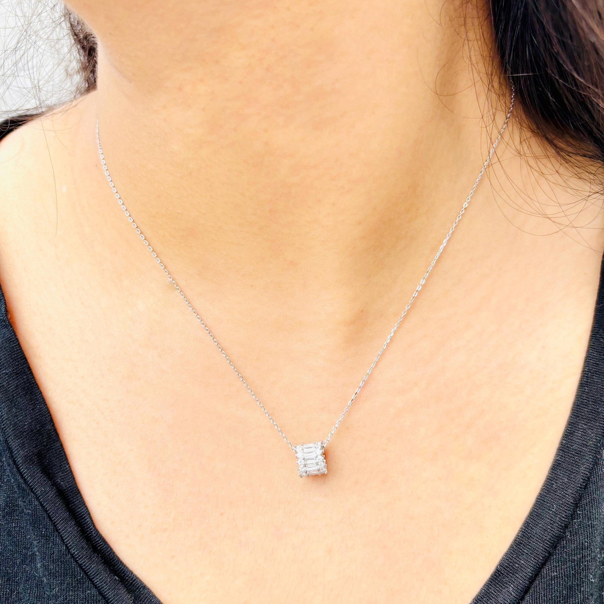 A minimalist 925 sterling silver necklace with a rectangular baguette-cut pendant, worn on a woman, showcasing its elegant and timeless design.