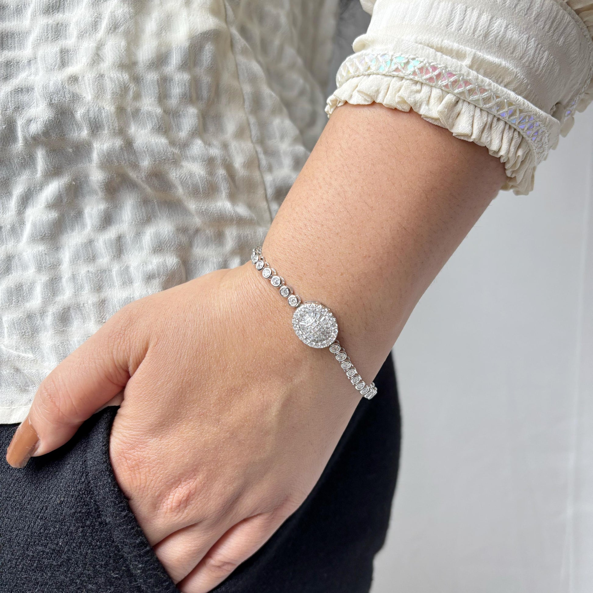 925 sterling silver bracelet with a round halo centerpiece of sparkling CZ stones, worn on a woman's wrist against a soft neutral background.