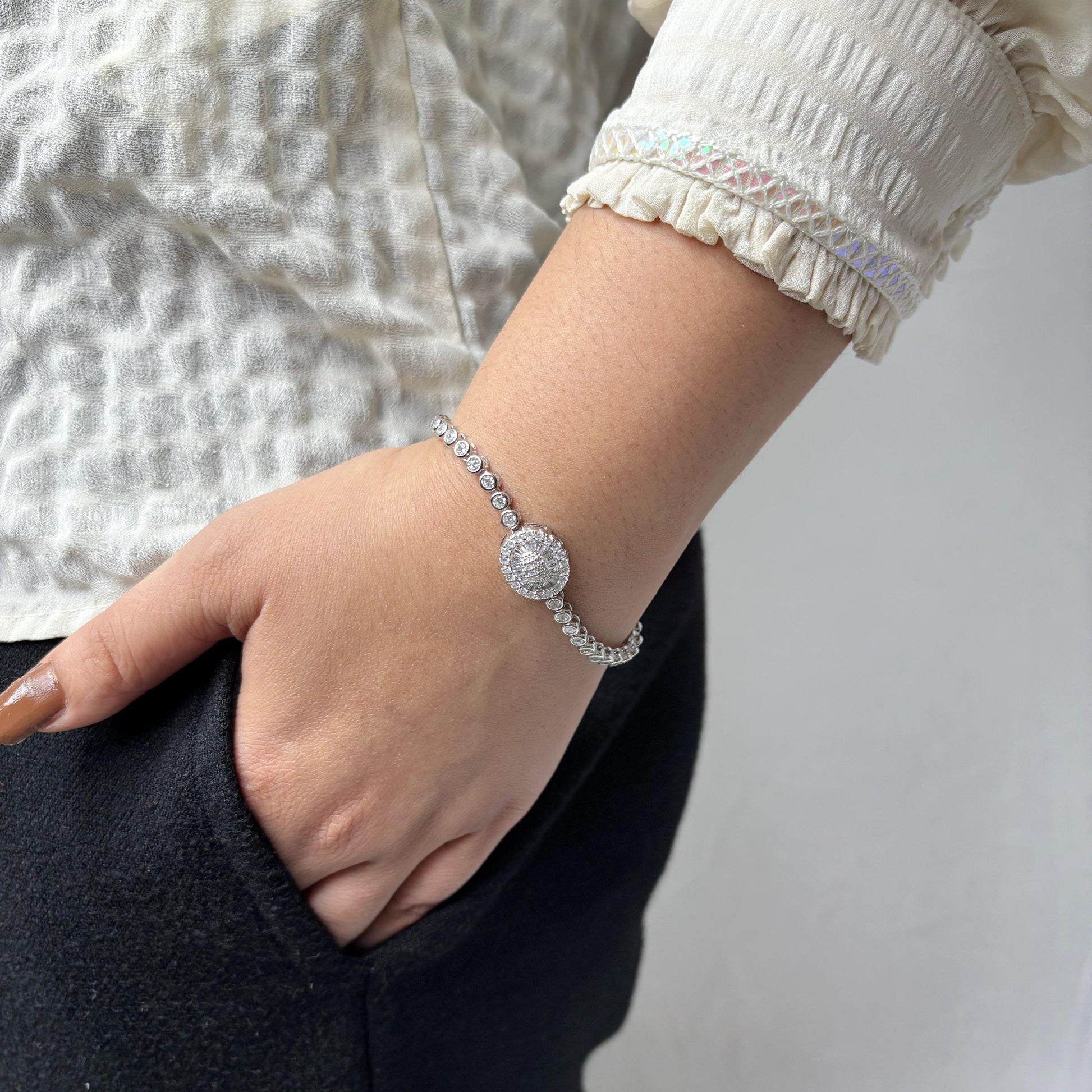 925 sterling silver bracelet with a round halo centerpiece of sparkling CZ stones, worn on a woman's wrist against a soft neutral background.