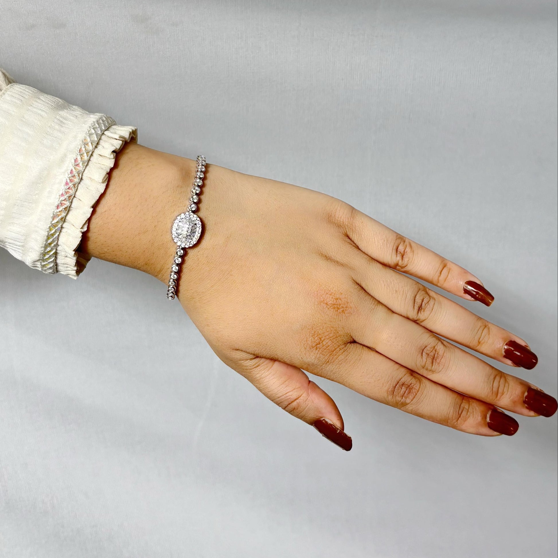 925 sterling silver bracelet with a round halo centerpiece of sparkling CZ stones, worn on a woman's wrist against a soft neutral background.