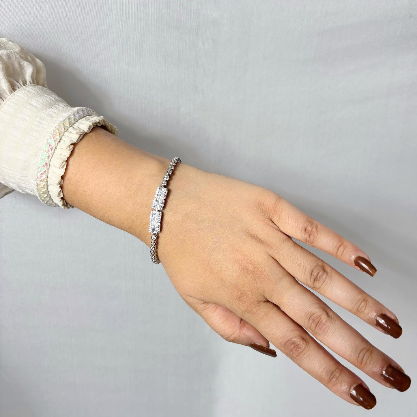 A dazzling 925 sterling silver bracelet featuring two rectangular centerpieces with pavé-set stones, worn on a woman’s wrist against a neutral background.
