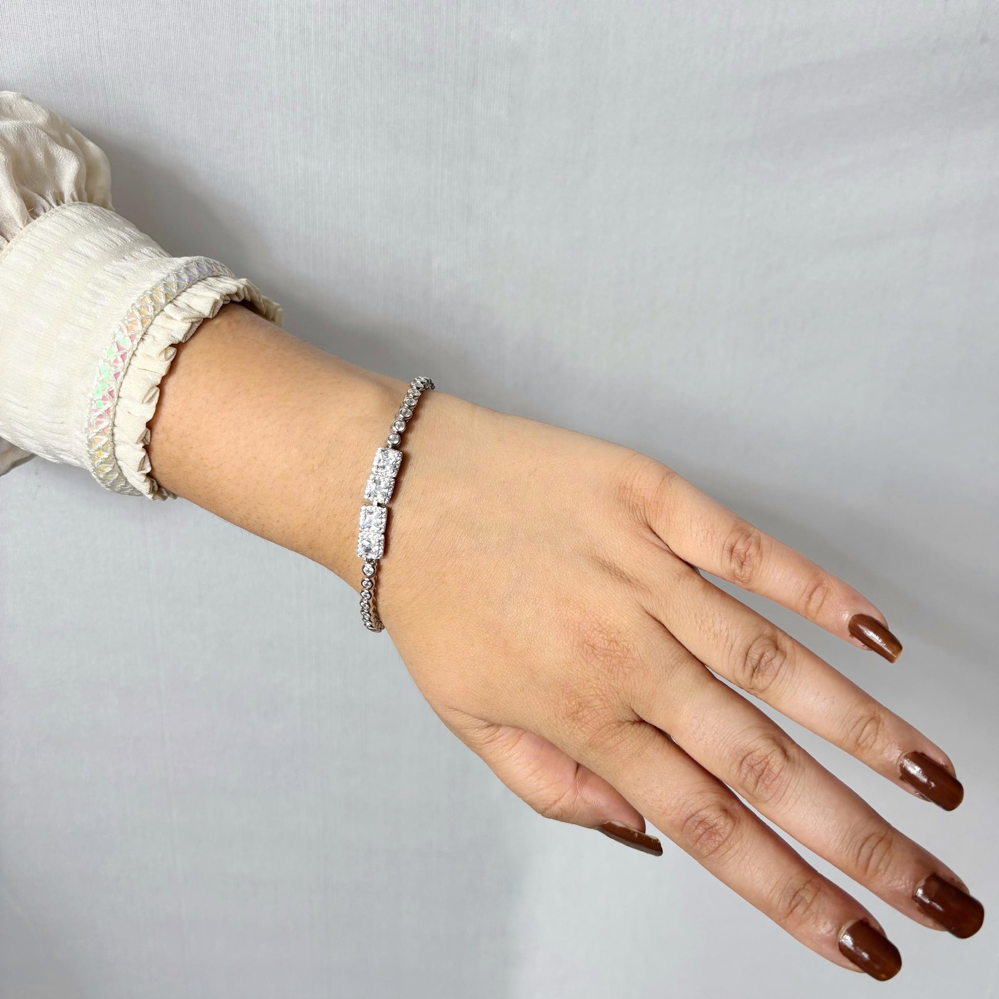 A dazzling 925 sterling silver bracelet featuring two rectangular centerpieces with pavé-set stones, worn on a woman’s wrist against a neutral background.