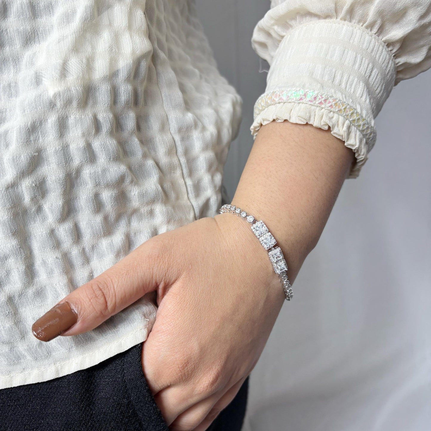 A dazzling 925 sterling silver bracelet featuring two rectangular centerpieces with pavé-set stones, worn on a woman’s wrist against a neutral background.