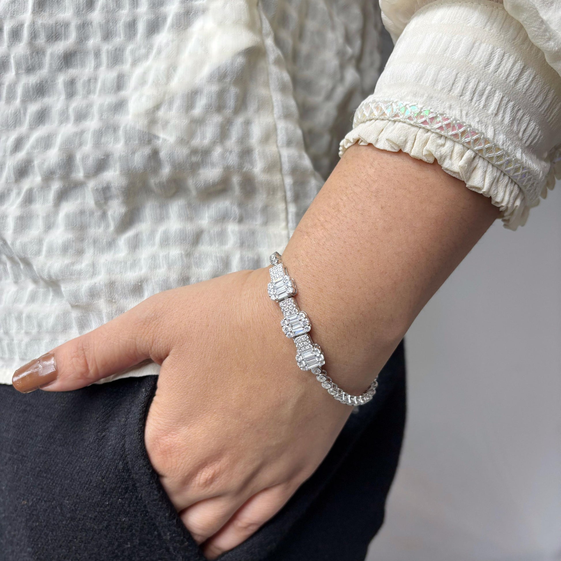 A luxurious 925 sterling silver bracelet featuring emerald-cut CZ stones in a prong setting, worn on a woman's wrist with a neutral background.