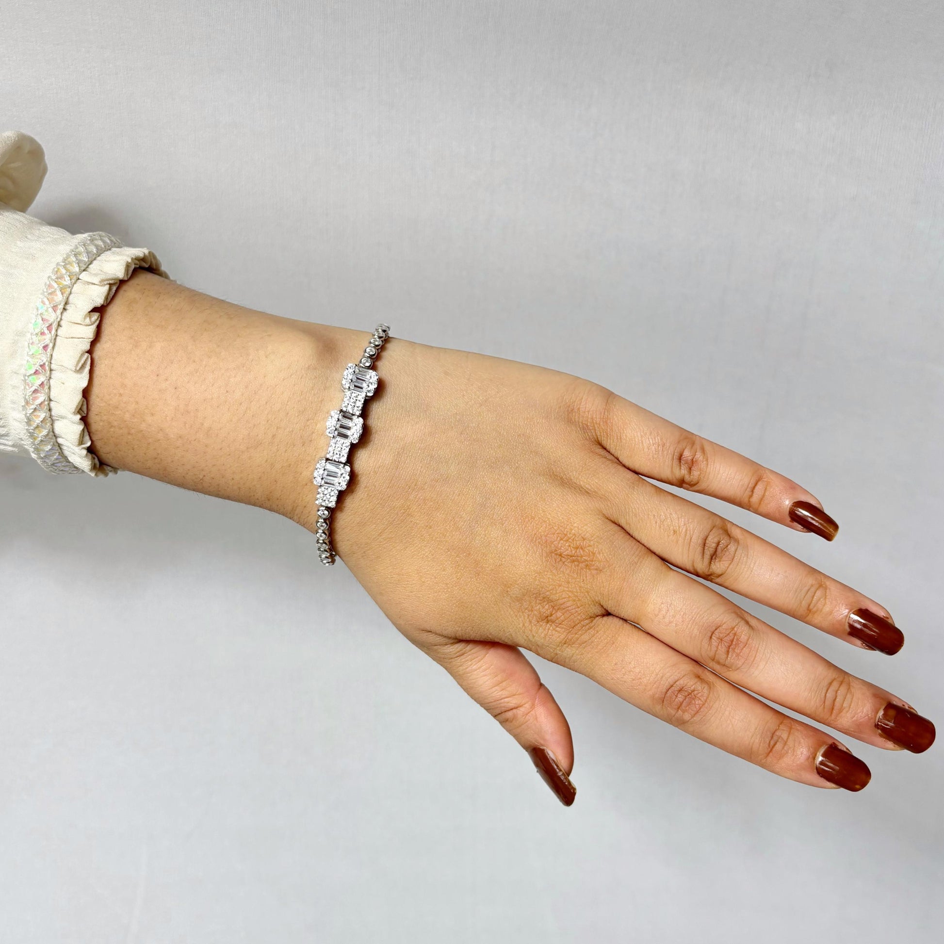 A luxurious 925 sterling silver bracelet featuring emerald-cut CZ stones in a prong setting, worn on a woman's wrist with a neutral background.