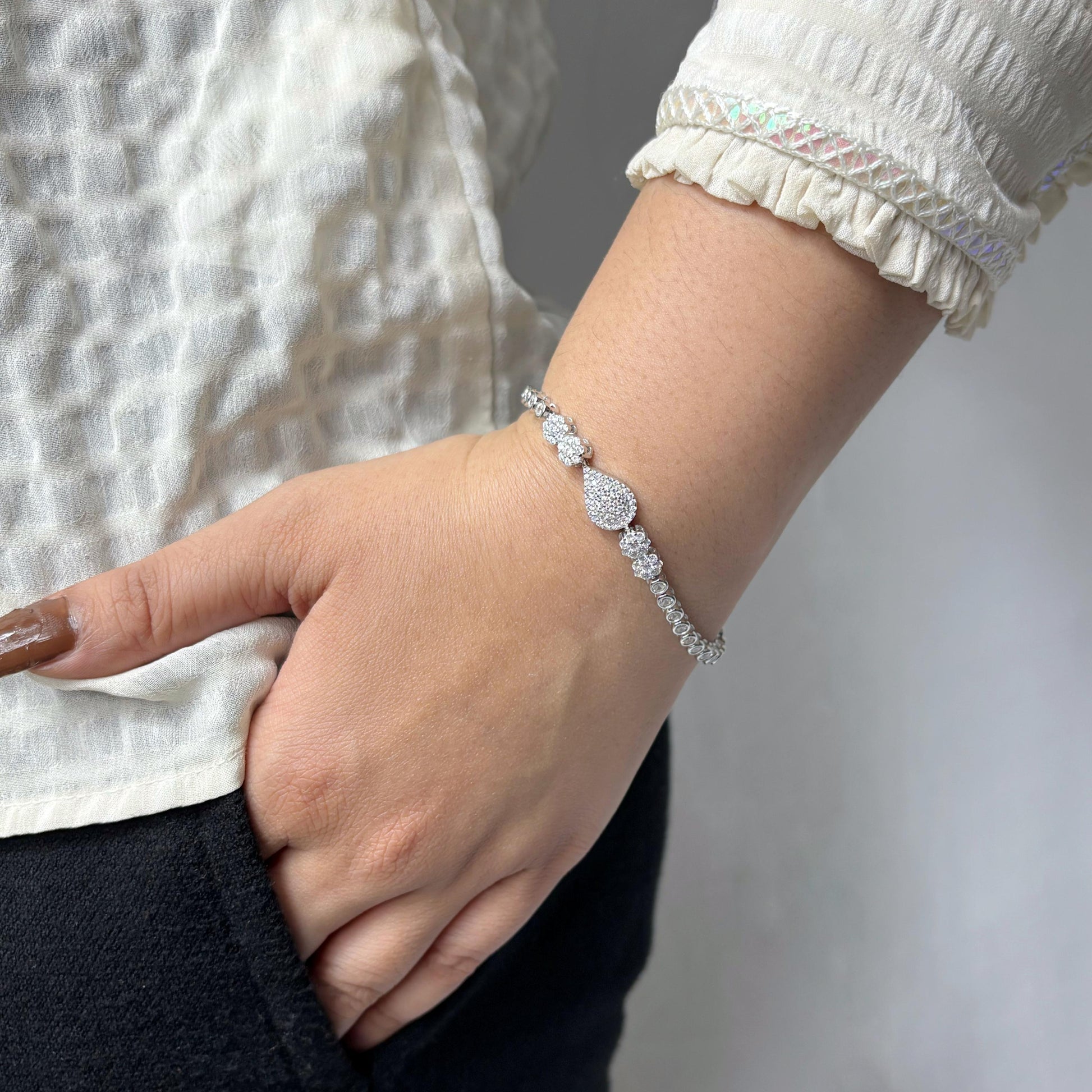 925 sterling silver bracelet featuring a central teardrop-shaped CZ stone cluster, worn on a woman's wrist with a neutral outfit.